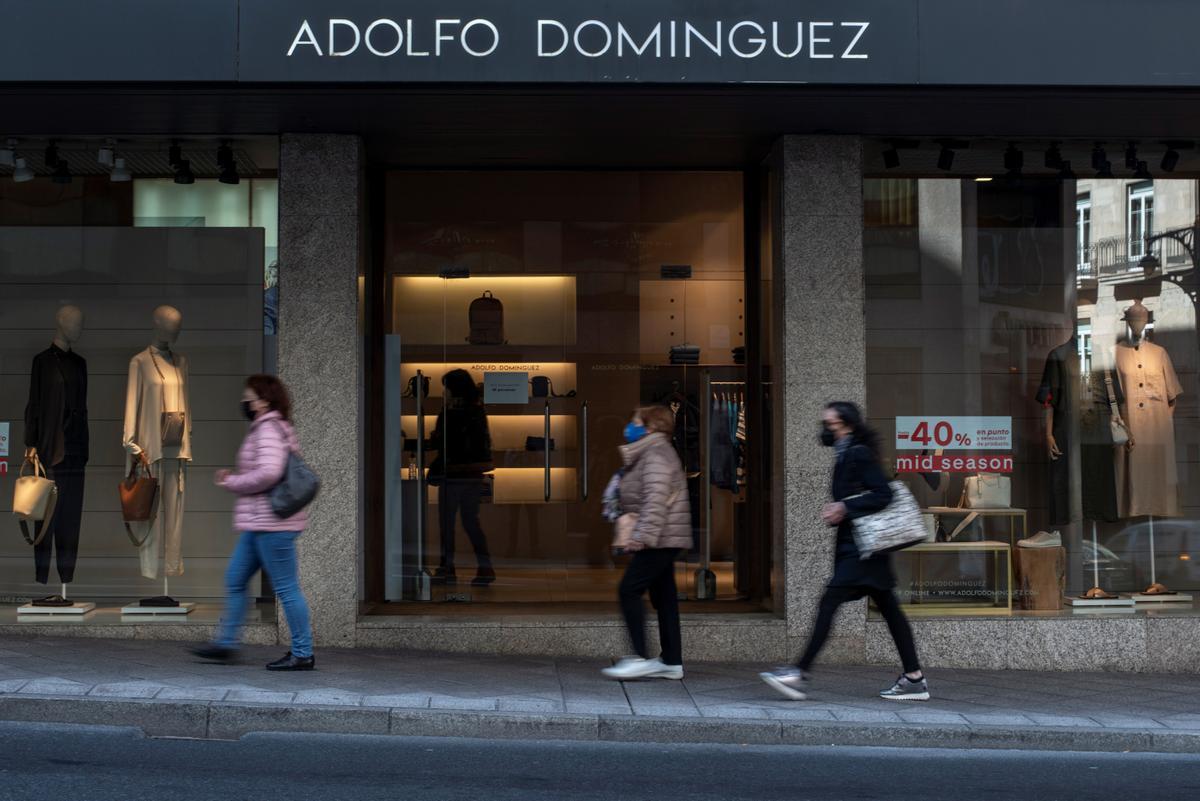 Varias personas pasan delante de una tienda de Adolfo Domínguez. EFE/ Brais Lorenzo/Archivo