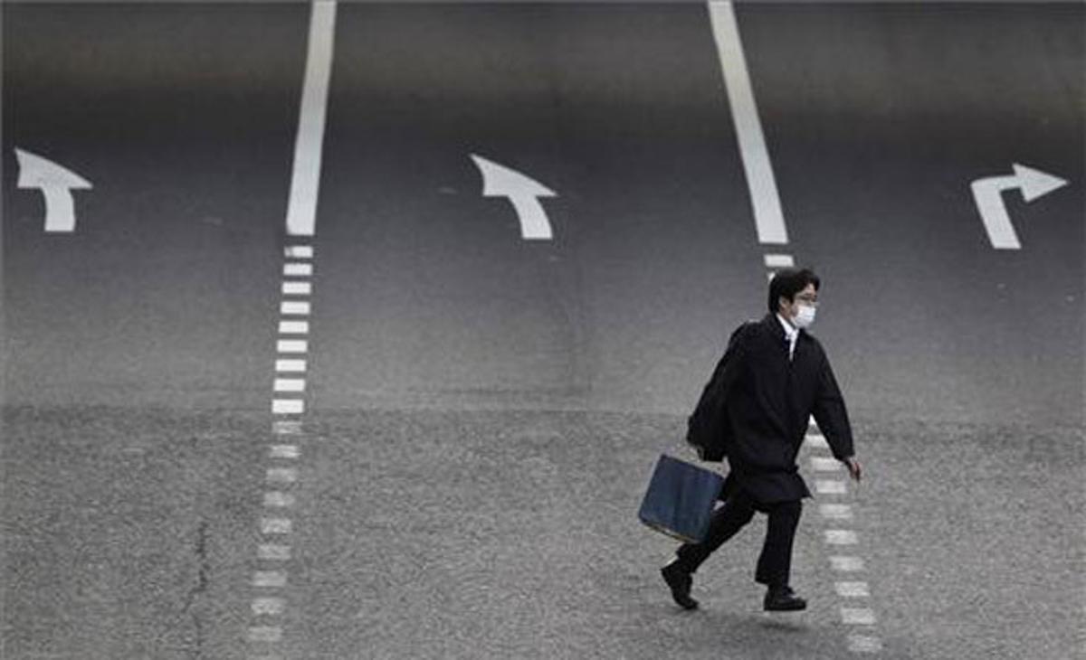 Un home travessa un carrer de Tòquio. Un home travessa un carrer de Tòquio.