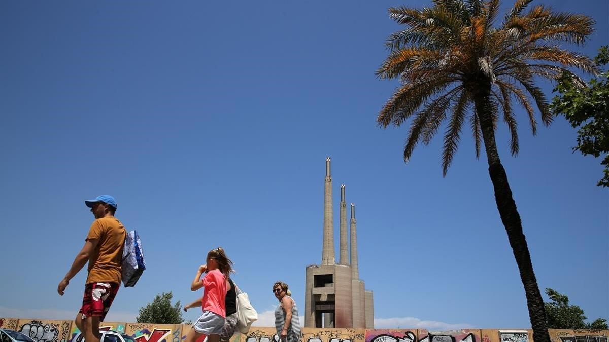 Unas personas pasan por delante de Les Tres Xemeneies de Sant Adrià de Besós, el 24 de julio del 2018