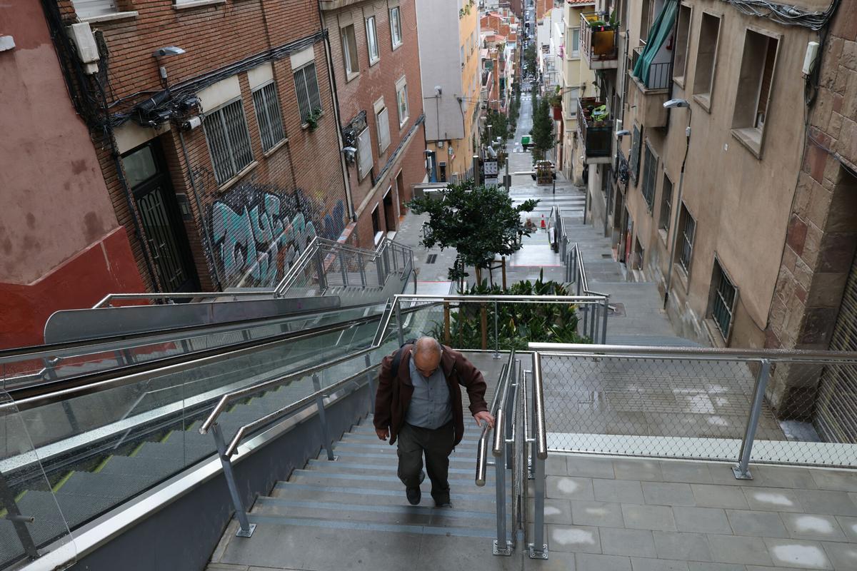 Un hombre sube por las escaleras del hormigón al lado de las mecánicas en la Baixada de la Glòria.