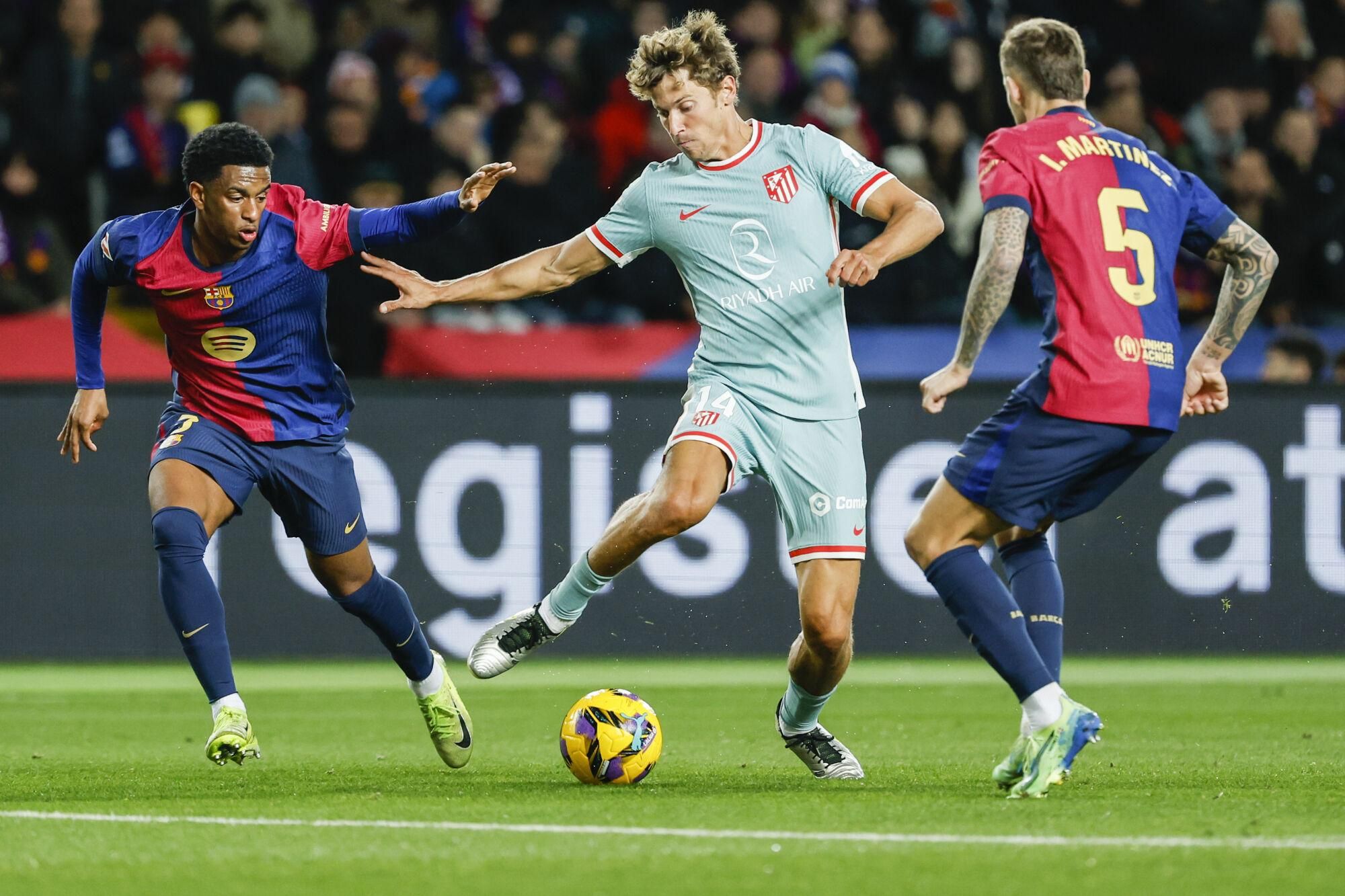 Atletico Madrid's Marcos Llorente, centre, duels for the ball with Barcelona's Inigo Martinez and Barcelona's Alejandro Balde during the Spanish La Liga soccer match between Barcelona and Atletico Madrid at the Lluis Companys Olympic Stadium in Barcelona, Spain, Saturday, Dec. 21, 2024. (AP Photo/Joan Monfort). EDITORIAL USE ONLY/ONLY ITALY AND SPAIN