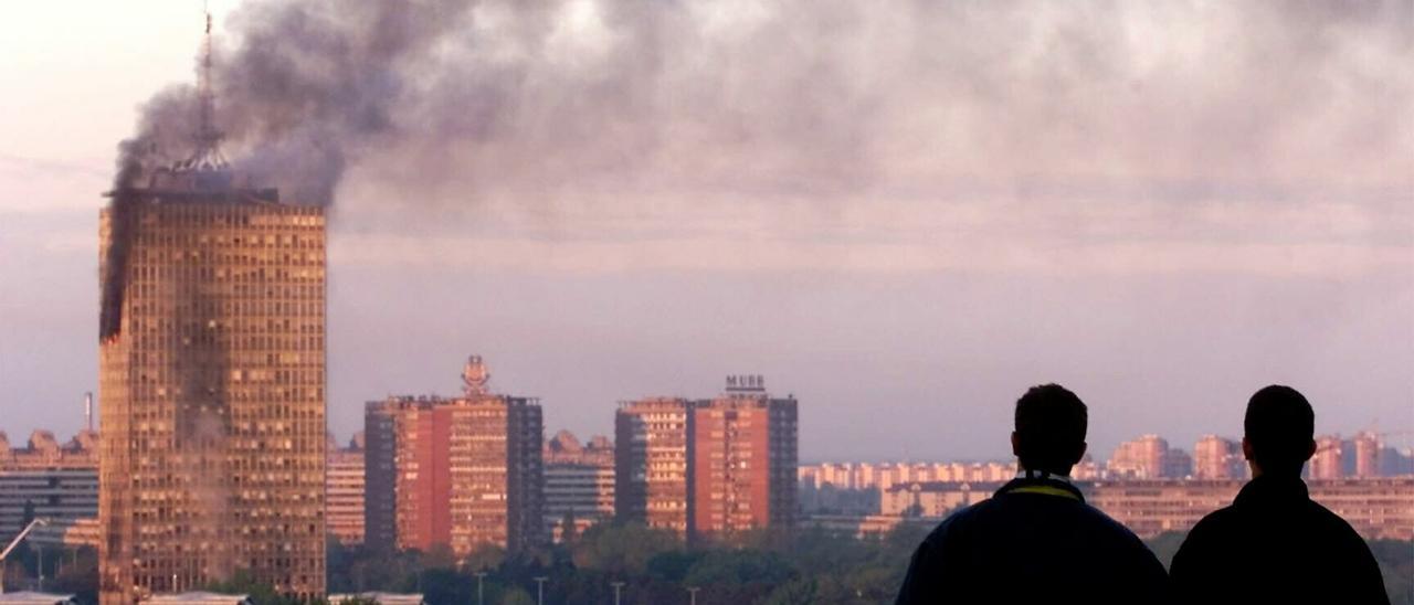 Dos hombres observan el 21 de abril de 1999 un edificio en llamas de Belgrado donde acaban de impactar tres misiles disparados por aviones de la OTAN. AP PHOTO/Srdjan Ilic