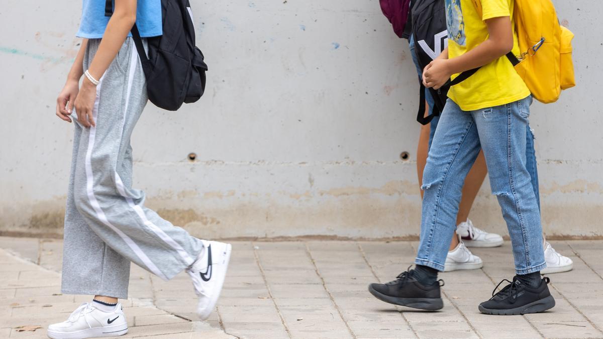 Varios alumnos salen del centro en pantalones largos.