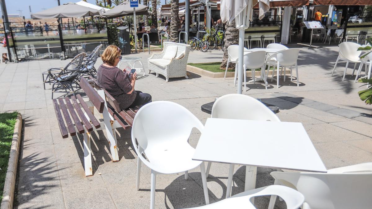 Un banco público rodeado de mesas y sillas en el paseo de Juan Aparicio de Torrevieja