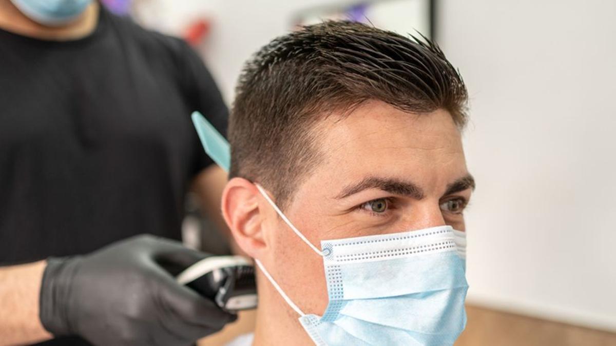 Una peluquería realizando un corte de pelo a un joven