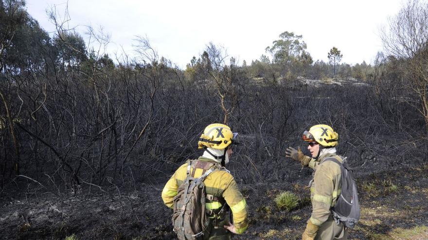 Dos bomberos contemplan monte ardido en Alperiz (Lalín) en abril del año pasado. |   // BERNABÉ/JAVIER LALÍN
