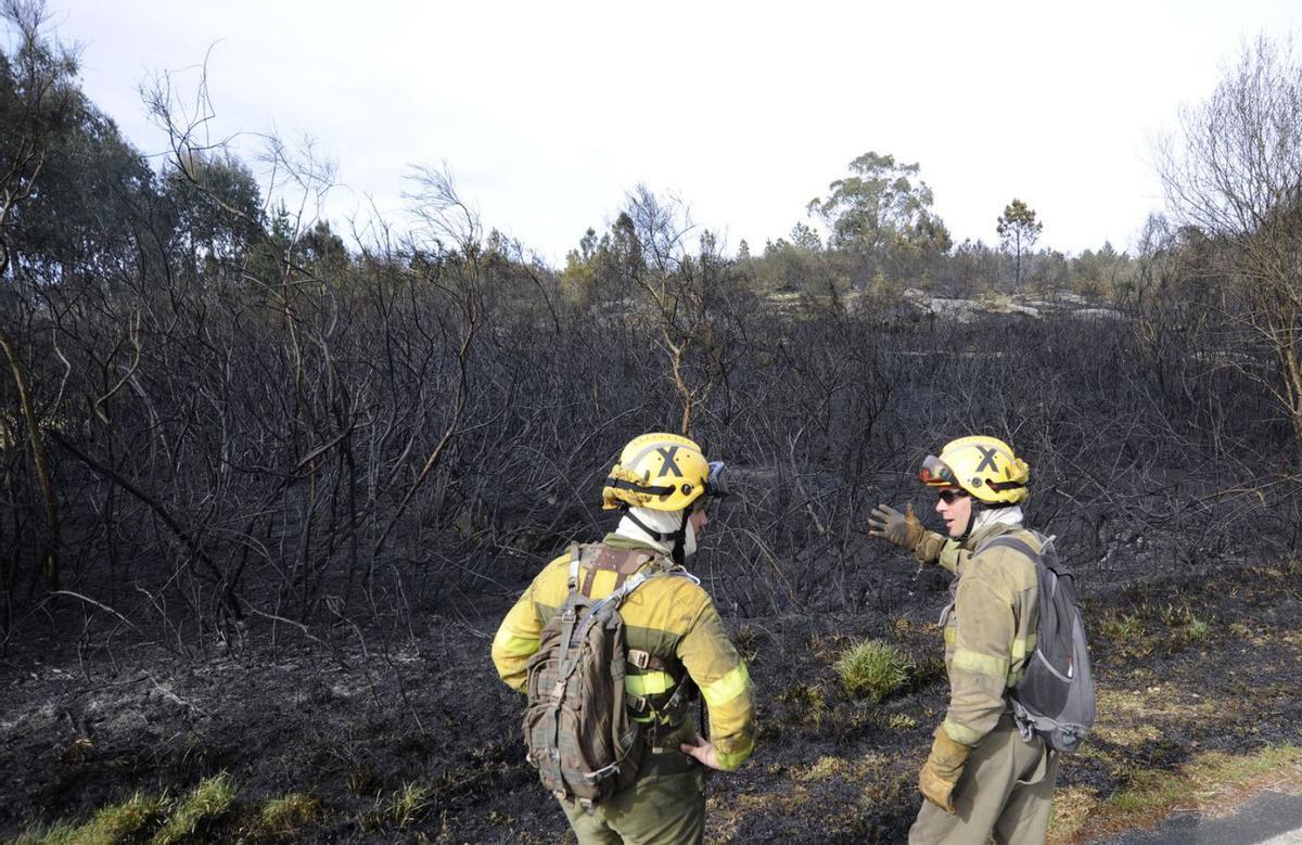 Dos bomberos contemplan monte ardido en Alperiz (Lalín) en abril del año pasado. | // BERNABÉ/JAVIER LALÍN