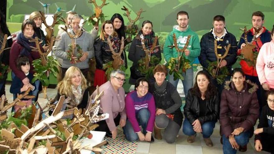 Componentes del proyecto de integración social y comerciantes de Tineo, con el reno, emblema de la campaña de Navidad.