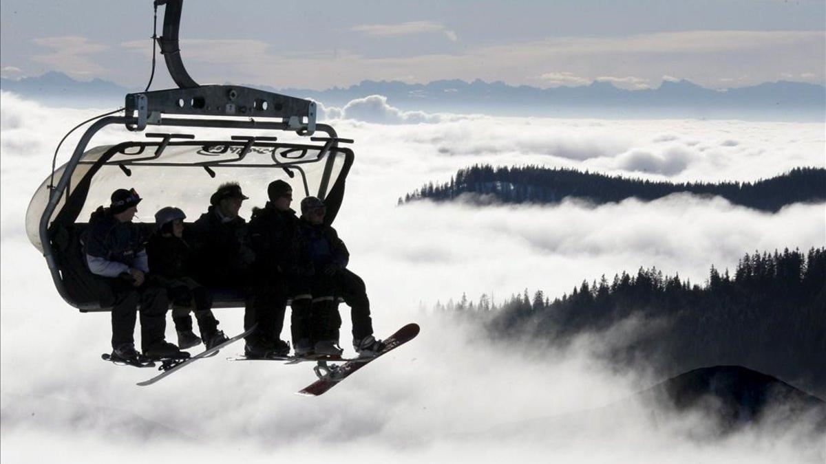 Un grupo de esquiadores y aficionados al snowboard suben en telesilla a la soleada cumbre del Feldberg (Alemania).