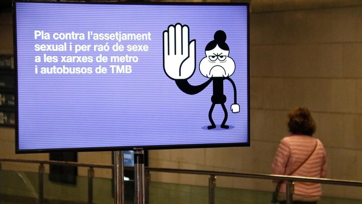 Una dona camina al costat d un cartell contra l assetjament al vestibul del metro a Universitat el 5 03 2021 (horitzontal) Blanca Blay ACN