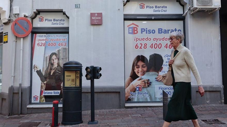 Una mujer pasa ante los anuncios de una firma inmobiliaria en una calle de Santa Cruz de Tenerife. | | MARÍA PISACA