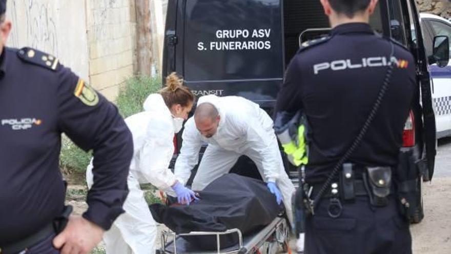 Empleados de la funeraria trasladan el cadáver.