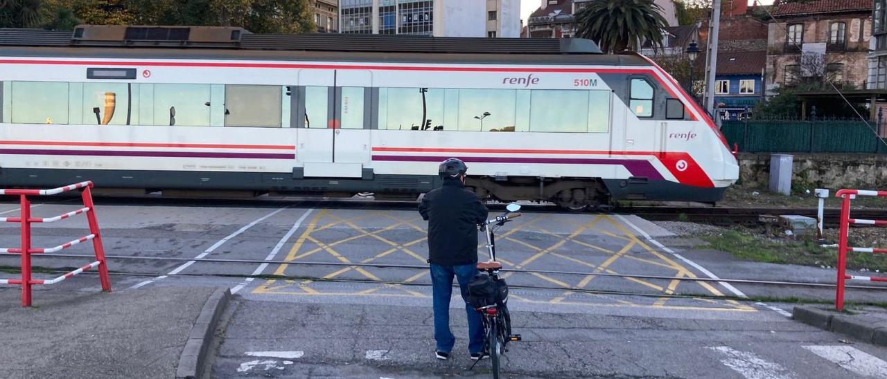 Un ciclista aguarda el paso del tren para cruzar las vías en El Muelle. | F. L. J.