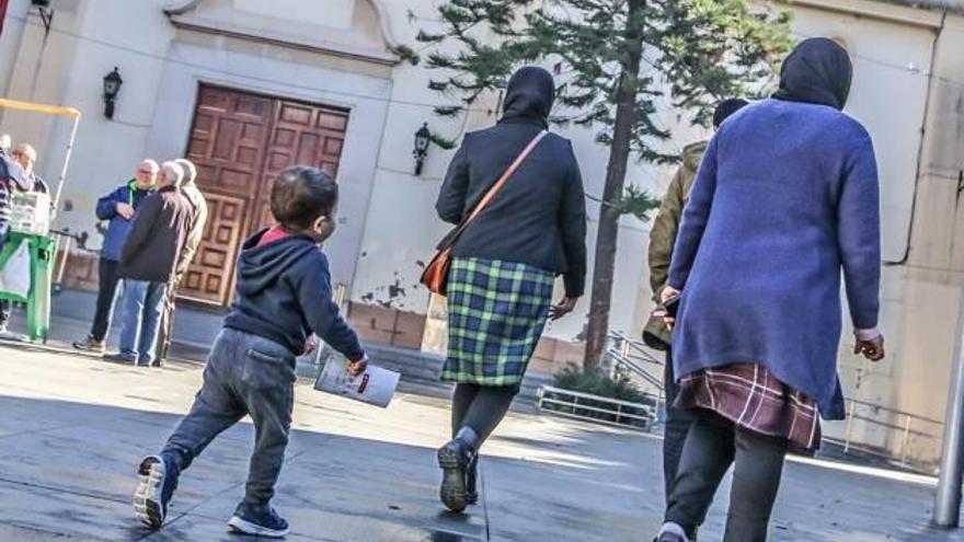 Dos mujeres musulmanas pasean junto a un niño por la plaza de la Constitución de Almoradí.