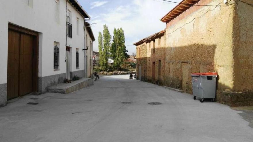 Varios vecinos sentados a la sombra en la calle San Pedro, recién pavimentada, en La Milla de Tera.