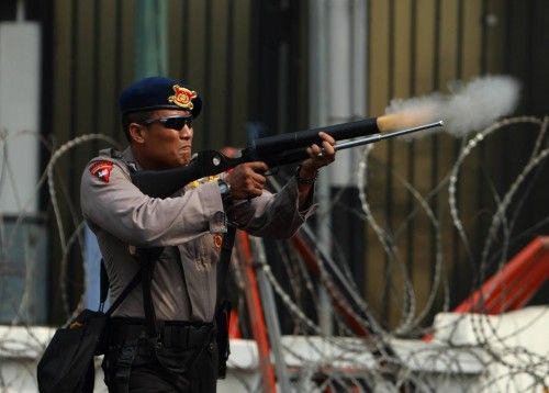 Policeman shoots tear gas canister towards Indonesian Muslim protesters during a demonstration in Jakarta