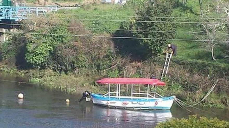 Un agente de Protección Civil baja a la orilla con una escalera.