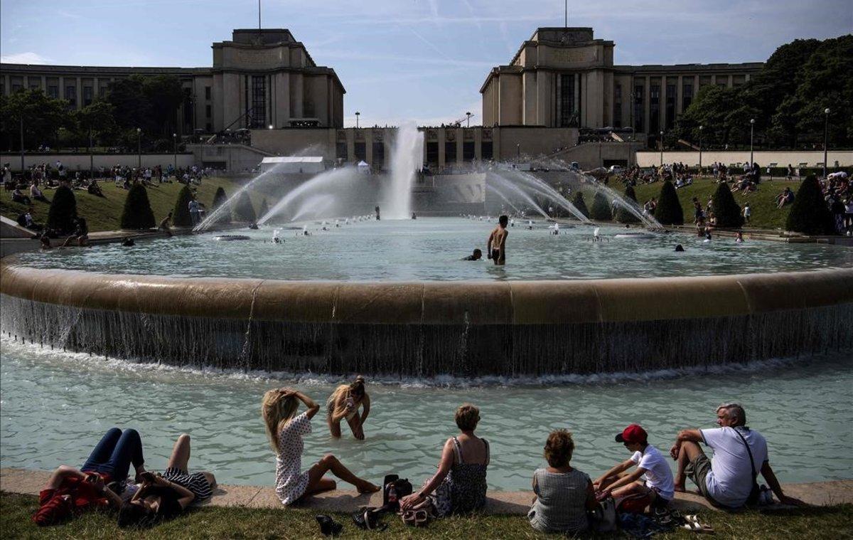Jóvenes toman el sol y se refrescan en la explanada de Trocadero, en París.