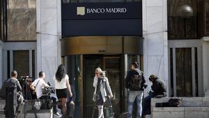 Varios periodistas esperan a las puertas de la sede del Banco de Madrid.