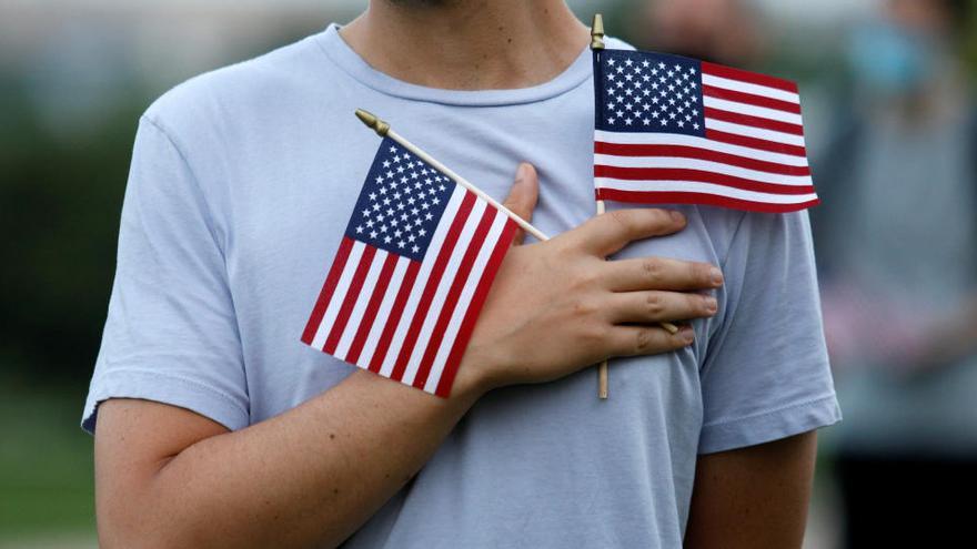 Un hombre sostiene dos banderas de EEUU