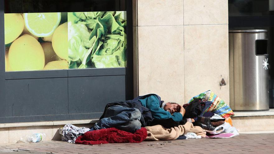 Un indigente duerme a las puertas de un supermercado de Málaga capital.