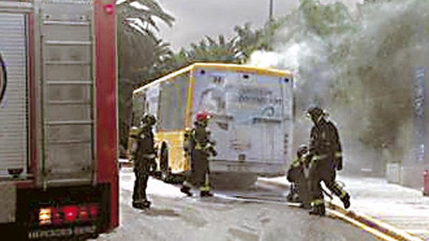 Los bomberos, junto la guagua incendiada en el Campus.