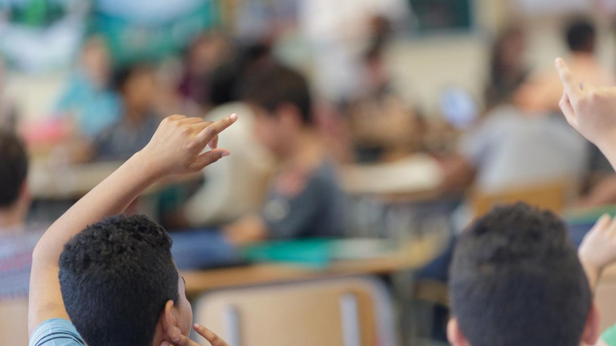 Dos alumnes aixequen el braç durant una classe, imatge d’arxiu.