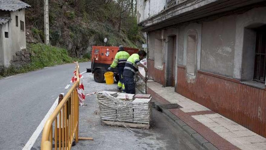 Dos operarios trabajan en la ampliación de la plataforma de la acera.