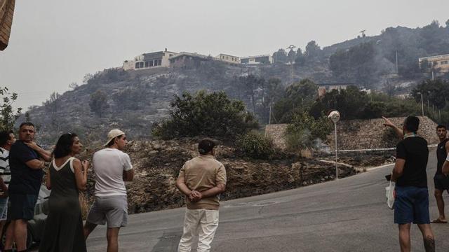Un grup de veïns de la Vall d’Uixó observen les cases envoltades pel foc, ahir.  | MANUEL BRUQUE / EFE