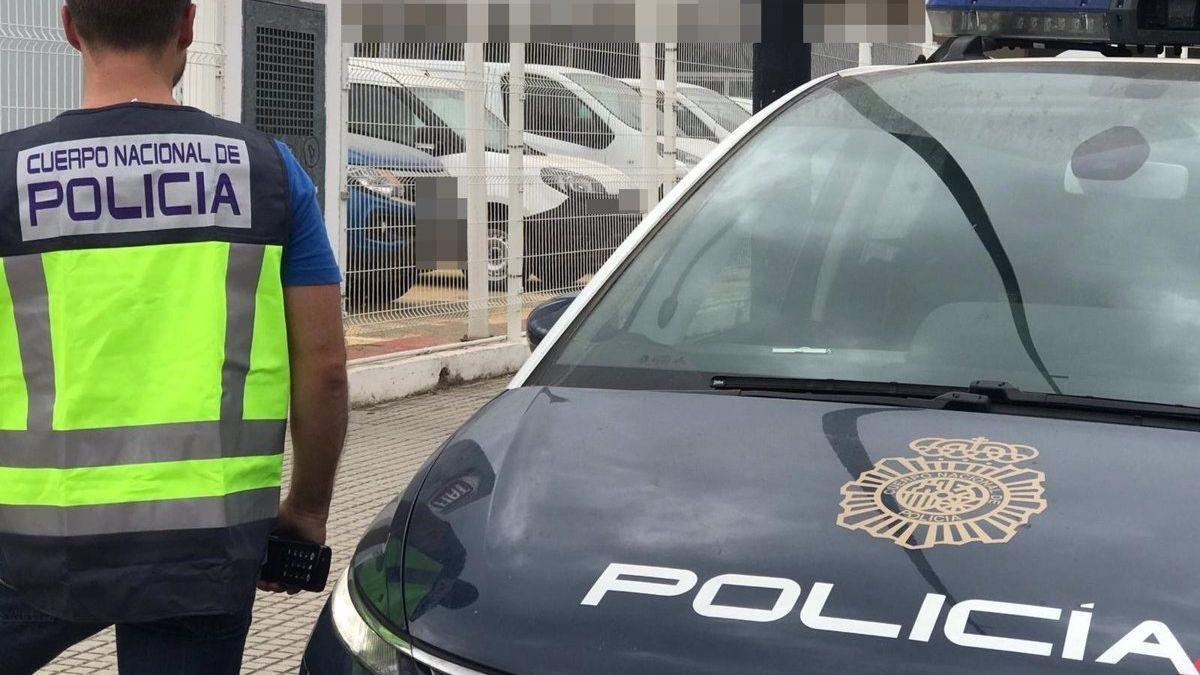 Un agente de Policía nacional junto a una patrulla.