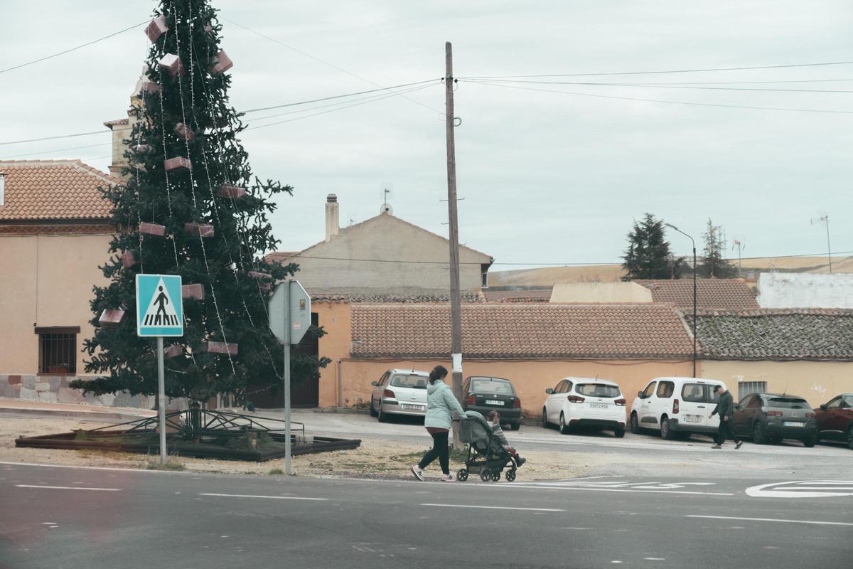 Una mujer pasea con el carrito de bebé por una de las calles del pueblo.