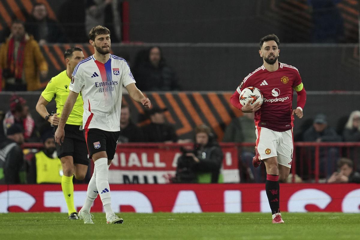 Manchester United's Bruno Fernandes holds the ball after scoring from the penalty spot side's third goal during the Europa League quarter final second leg soccer match between Manchester United and Olympique Lyon in Manchester, Britain, Thursday, April 17, 2025. (AP Photo/Jon Super)