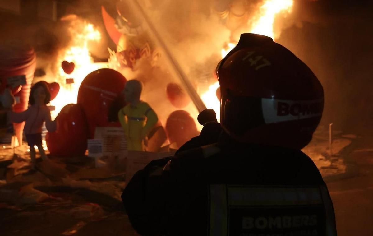 Un bombero controla el fuego mientras se quema una falla