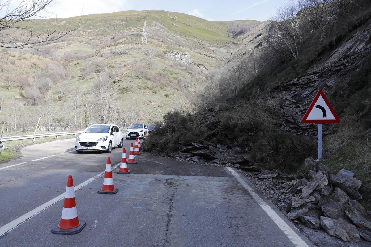 Varios vehículos pasan junto al argayo.