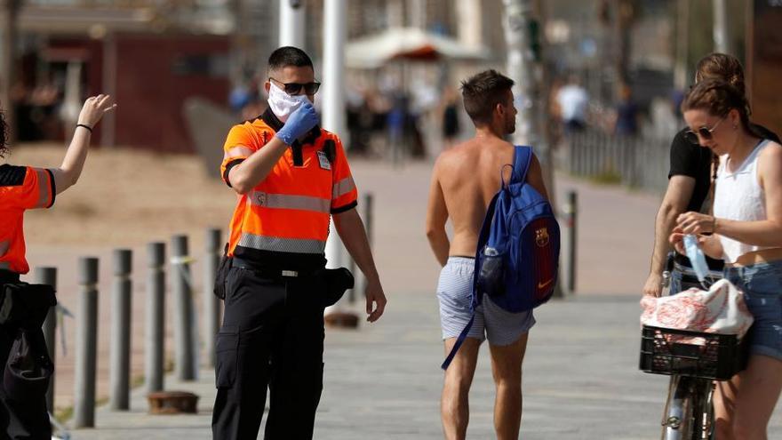 Agentes Civicos indican a una joven que se coloque la mascarilla en Barcelona.