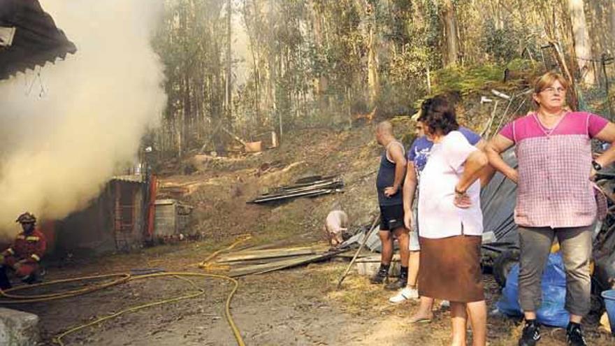 Vecinos ven la intervención de un bombero del Ejército (izq.) en el incendio de Pontevedra.  // Noé Parga