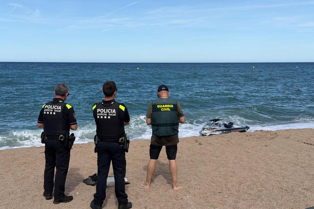 Dos agents de la Policia Local de Pals i un de la Guàrdia Civil davant de la moto que han trobat a la sorra del jove desaparegut a Roses.