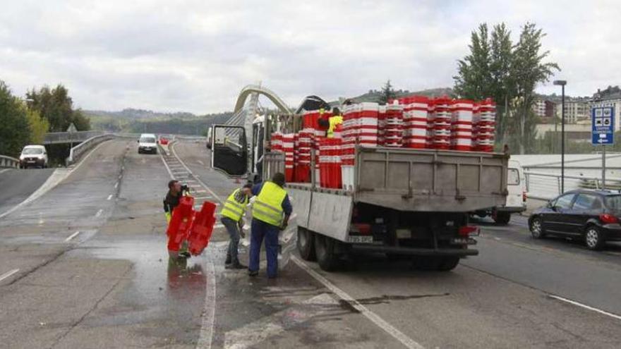 Momento en que los operarios recogían en la tarde de ayer los pivotes para reabrir al tráfico el puente del Milenio. // Jesus Regal