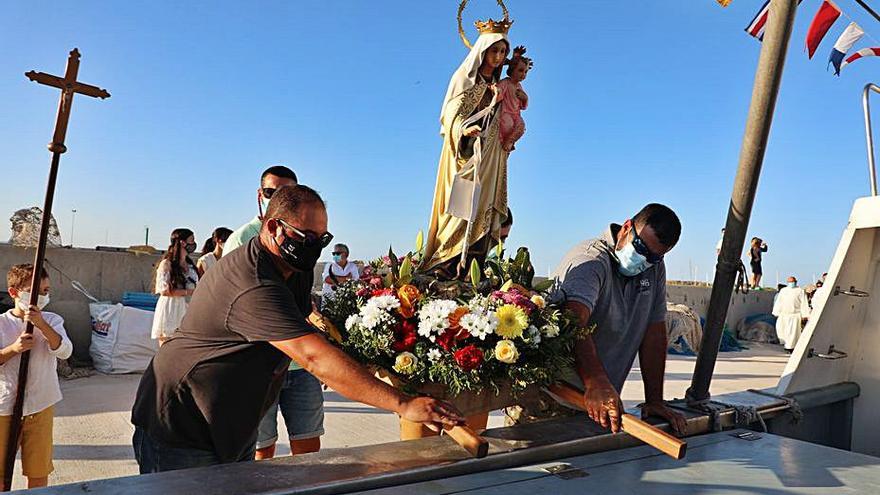 Los pescadores embarcan la imagen de la Virgen. | C.C.