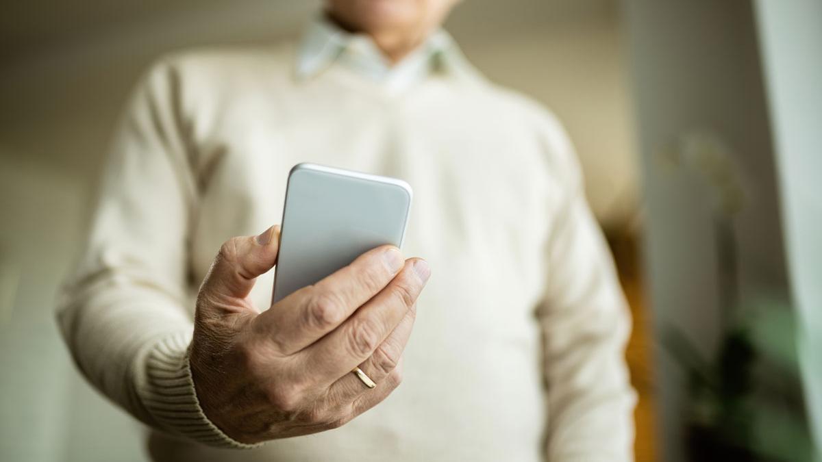 Un hombre observa su teléfono móvil, en una imagen de recurso.