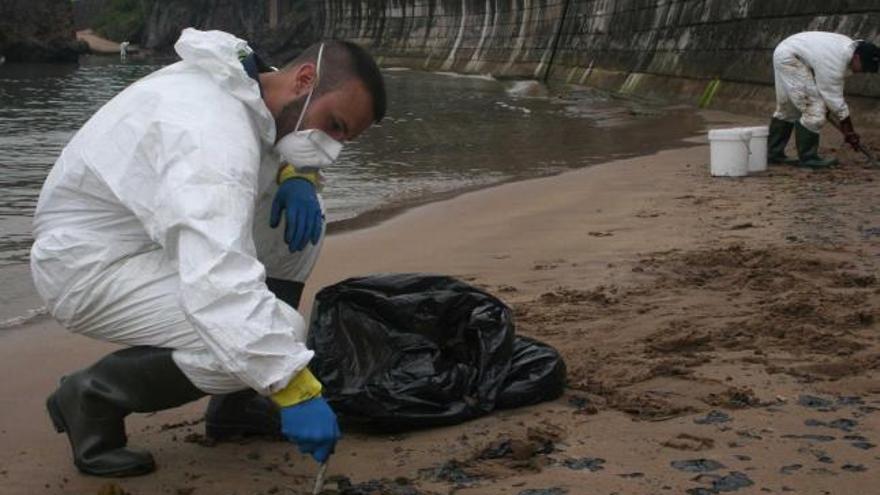 Dos operarios contratados por el Ayuntamiento de Carreño, realizando la limpieza de las playas el pasado verano.