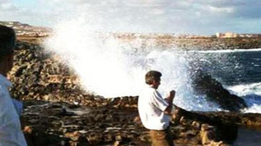 David Calzada, al fondo, en el salpicadero de la espuma de mar de donde se alimentan las salinas de la isla canaria de Fuerteventura.