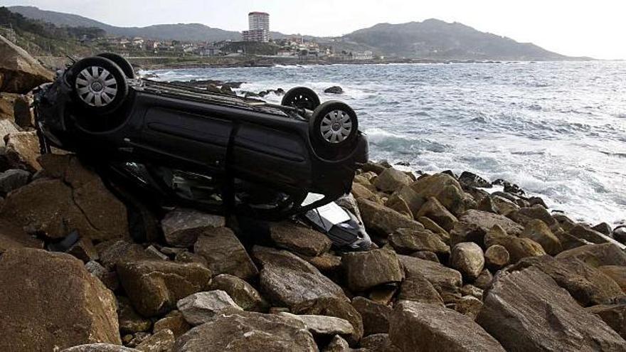 El coche volcado sobre las rocas, cerca del agua, en la costa al sur de Baiona. / la opinión