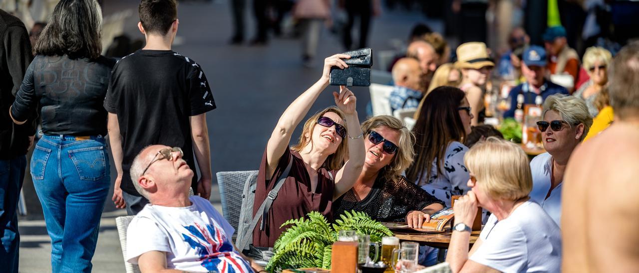 Dos turistas haciéndose un selfi en la terraza de una cafetería en Benidorm