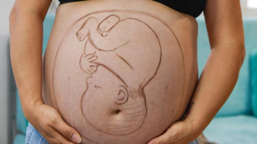 Un vientre pintado con la forma de un bebé durante un taller creativo.