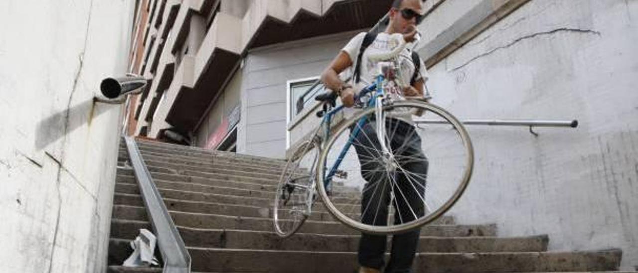 Un ciclista baja su bicicleta por las escaleras del paso de Germanías.