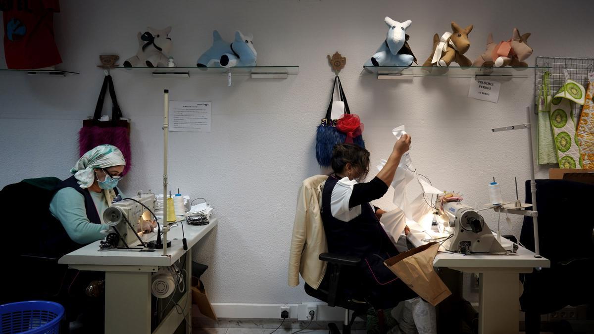 Dos mujeres confeccionan mascarillas en un taller de la asociación Apramp