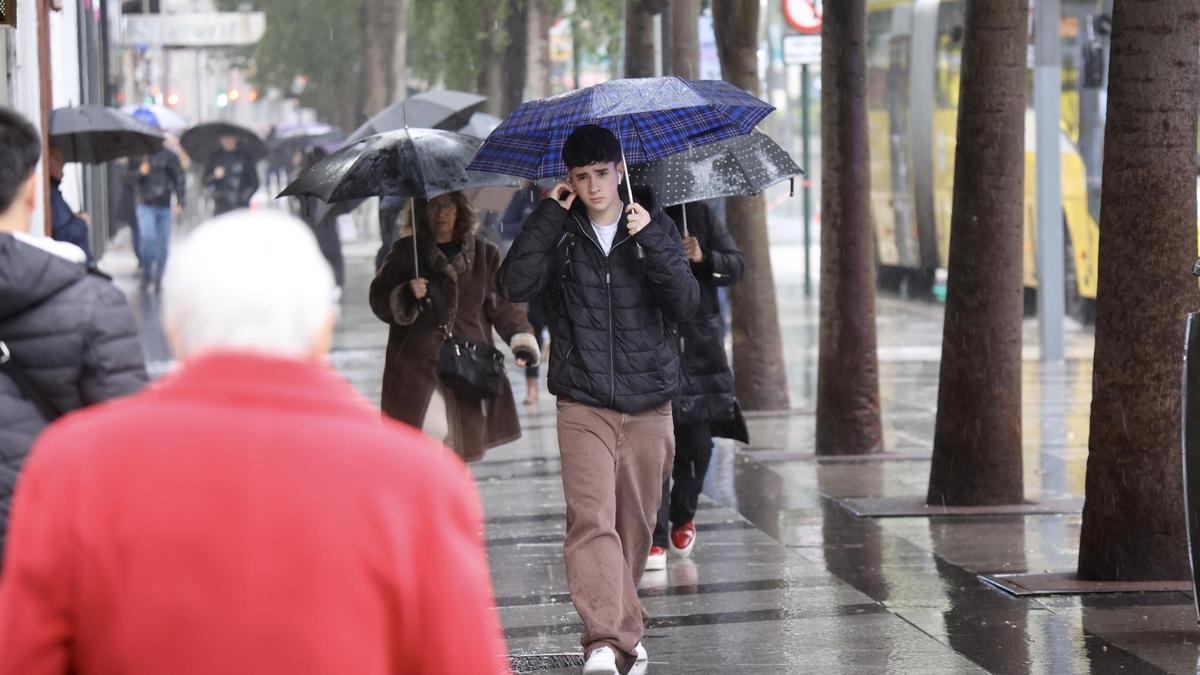 Los murcianos caminan bajo la lluvia por la Gran Vía de Murcia.