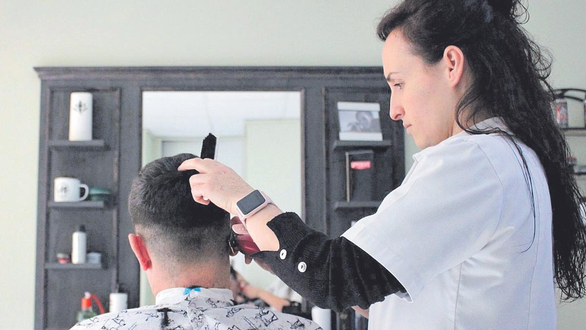 Una peluquera atiende a un cliente en Paniza (Zaragoza)