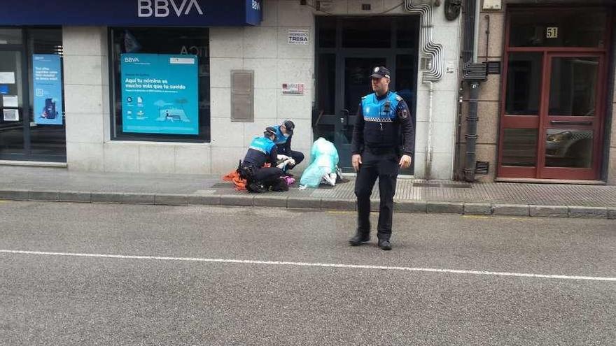 La sanitaria y los agentes de la Policía Local ayudan a la mujer, en la calle Libertad.